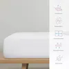 A white fitted sheet is shown on a wooden surface, with icons and text describing its features on the right side of the image. Produktbild-Vorschau