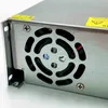 A close-up view of the side of a metal power supply unit, showing a fan grill with a fan inside and some warning labels. Podgląd zdjęcia produktu