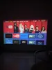 A projector screen displaying a smart TV interface with various app icons and promotional images of people. Produktbild-Vorschau