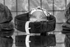 A close-up shot of the back of a black leather watch band with a silver buckle, resting on a reflective surface. Produktbild-Vorschau