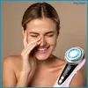 A woman is smiling and holding a facial massage device to her face. Náhľad obrázku produktu