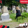 A woman sits on a black bench in a cemetery, looking at a gravestone. Voir les images du produit