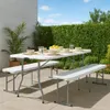 An outdoor patio setting with a white folding table and two white benches set up for a meal. Produktbild-Vorschau