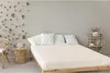 A bedroom scene with a bed, chair, and shelf. Produktbild-Vorschau