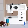 A white sewing machine is displayed on a table with spools of thread in the foreground. Produktbild-Vorschau