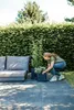 A woman is tending to plants in pots on a patio next to a sofa. Produktbild-Vorschau