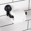 A black toilet paper holder with a roll of toilet paper attached, mounted on a white tiled wall with black grout lines. Produktbild-Vorschau