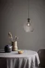 A table setting with a teapot, a cup, and a vase with dried flowers, under a pendant lamp. Produktbild-Vorschau