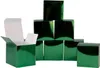 A group of shiny green boxes arranged in a pyramid shape, with one box open in the foreground. Produktbild-Vorschau