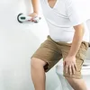 A person is using a grab bar in a bathroom next to a toilet. Produktbild-Vorschau