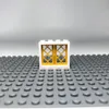 A white LEGO window frame with gold panes sits on a gray LEGO baseplate. Produktbild-Vorschau