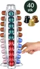 A hand is reaching for coffee capsules in a rotating dispenser. There are also loose coffee capsules shown in the background. Náhľad obrázku produktu