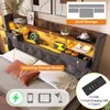 A bed with a headboard featuring integrated shelves, lighting, and storage boxes, along with a charging station. Produktbild-Vorschau