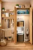 A well-organized laundry room or utility closet with shelves and cabinets filled with cleaning supplies, towels, and laundry accessories. Anteprima dell’immagine prodotto