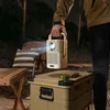 A person holding a portable projector outdoors at night, with camping furniture in the background. Produktbild-Vorschau