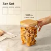 A hand is shown placing the lid on a glass storage jar filled with dried fruit, set on a marble countertop. Produktbild-Vorschau