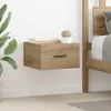 A wooden nightstand is mounted on a white wall next to a bed. A plant and books are on top of the nightstand. Produktbild-Vorschau