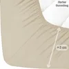 A close-up view of a cream-colored fitted sheet, showing the elasticized edge and a measurement indicator. Produktbild-Vorschau