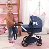 A young girl is playing with a doll stroller in a room with pink and white decor. Produktbild-Vorschau