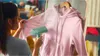 A person is steaming a pink hoodie with a handheld garment steamer. Produktbild-Vorschau