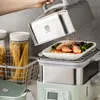 A hand is lifting the lid off a steaming food appliance, revealing a dish of shrimp and vegetables. Produktbild-Vorschau