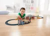 A young boy plays with a toy train set on a wooden floor in a room. Náhled obrázku produktu