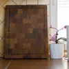 A wooden cutting board is placed on a kitchen counter next to a potted plant. Produktbild-Vorschau