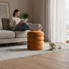 A woman reads a book on a sofa, with her feet resting on an orange ottoman. A small white dog lies on the rug nearby. Podgląd zdjęcia produktu