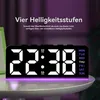 A digital alarm clock displaying the time and day of the week, with purple ambient light emanating from its base. Produktbild-Vorschau