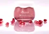 A jar of Frudia Pomegranate Nutri-Moisturizing Cream is displayed on a reflective white surface, surrounded by pomegranate seeds. Náhled obrázku produktu