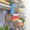 A collection of books organized on floating shelves with a patterned wallpaper background. Produktbild-Vorschau