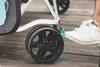 A close-up shot of a person's foot pressing a brake lever on a stroller or similar wheeled device. Produktbild-Vorschau
