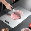 A person is chopping meat on a stainless steel cutting board. Produktbild-Vorschau