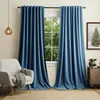 A living room scene with blue velvet curtains framing a window, a chair with a blanket, and a side table with a Christmas-themed picture. Voir les images du produit