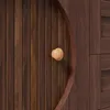A close-up view of a wooden cabinet door with a round wooden knob and a curved wooden handle. Voir les images du produit