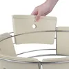 A hand is shown attaching a beige component to a circular metal structure, which appears to be part of a grill system. Produktbild-Vorschau