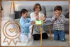 A mother and two children are playing a game of Jenga around a small table in a living room. An aroma diffuser is placed on the table. Produktbild-Vorschau