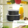 Two black cooking pots stacked inside a refrigerator, with a bottle of orange juice and mushrooms in the background. Voir les images du produit