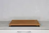 A wooden cutting board sits on a countertop in front of a textured gray wall. Produktbild-Vorschau