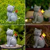 A collage of four images showing a solar-powered cat statue with a butterfly decoration in different lighting conditions. Produktbild-Vorschau