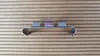 A metal clip is shown on a wooden background. Produktbild-Vorschau