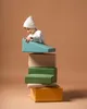 A child wearing a white beanie and white shirt is playing with a stack of colorful foam climbing blocks. Anteprima dell’immagine prodotto
