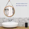 A round mirror with a wooden frame hangs on a white wall above a sink in a bathroom. Produktbild-Vorschau