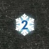 A snowflake graphic with the number 2 inside it, set against a dark, speckled background. Podgląd zdjęcia produktu