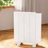 A white electric heater is placed on a wooden floor next to a window with sheer curtains. Náhľad obrázku produktu