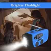 Two children are playing in a makeshift tent, illuminated by a bright flashlight from a blue and black emergency radio. Produktbild-Vorschau