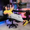 A man is relaxing in a gaming chair in a room with a computer setup. Produktbild-Vorschau