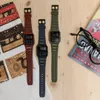 Three Casio calculator watches in different colors are laid out on a wooden surface next to a pair of glasses and a magazine. Produktbild-Vorschau