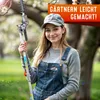 A young woman is holding a gardening tool in a park-like setting. Produktbild-Vorschau