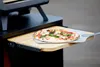 A pizza is being removed from a pizza oven using a pizza peel. Anteprima dell’immagine prodotto